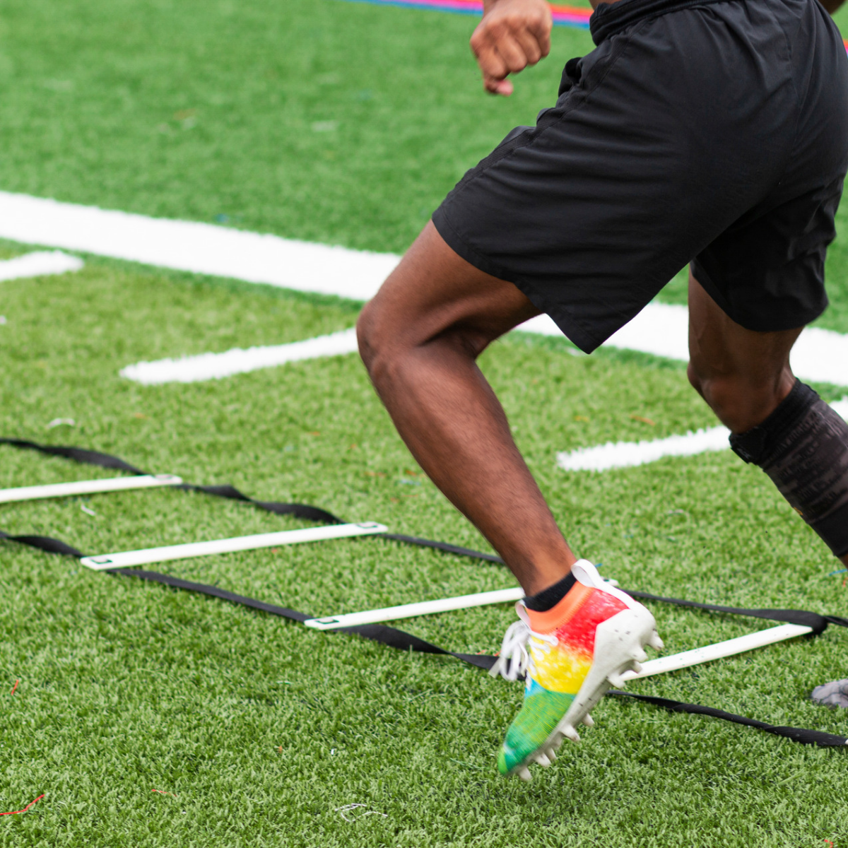 Man doing shuttle runs in football boots on football pitch exercise training