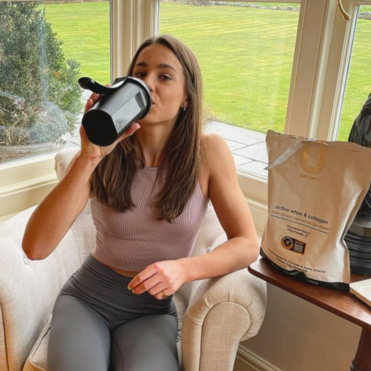 U Perform athlete sitting and drinking protein shake supplement after gym workout