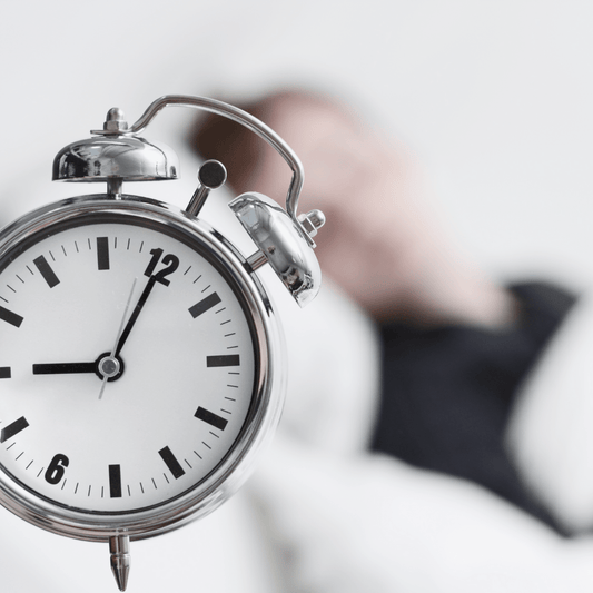 man in bed asleep with alarm clock in the foreground