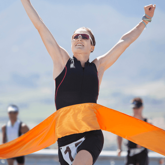 woman in running kit crossing a finish line with her arms in the air