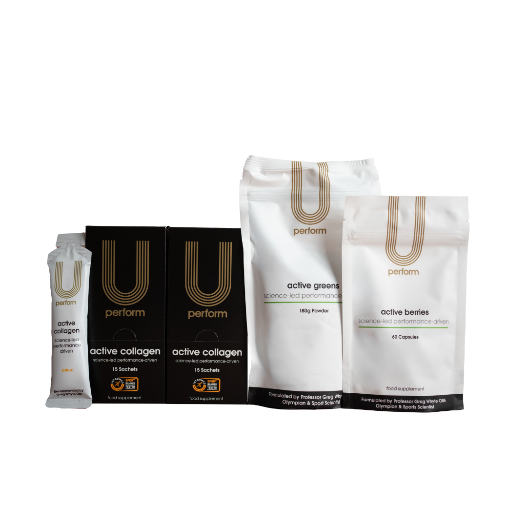 A lineup of U Perform branded supplements, including two black boxes and one sachet of "active collagen," a white pouch of "active greens" powder, and a smaller white pouch of "active berries" capsules. Packaging features minimalist gold and black design with the tagline "science-led performance-driven."